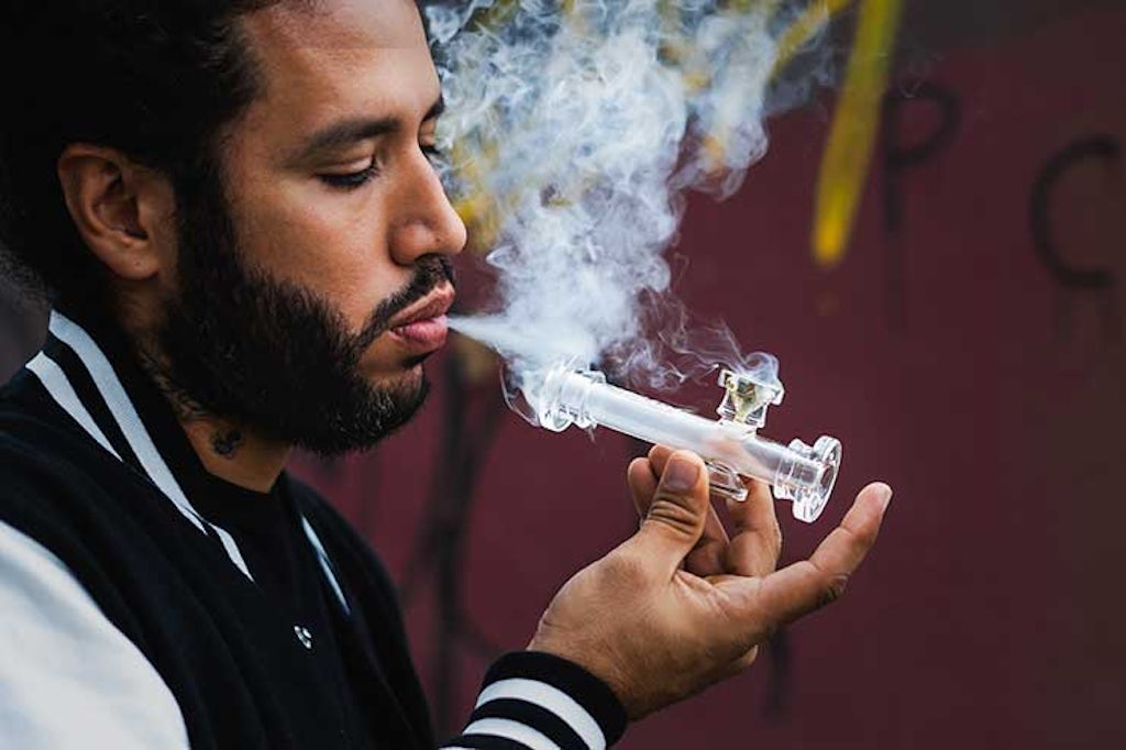 A man smokes marijuana from a glass pipe