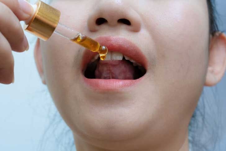 A young woman takes a cannabis oil tincture