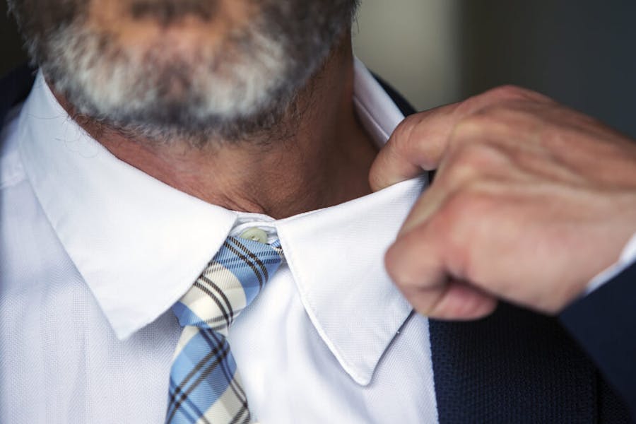 Homem relaxa a gola da camisa ao sentir taquicardia.