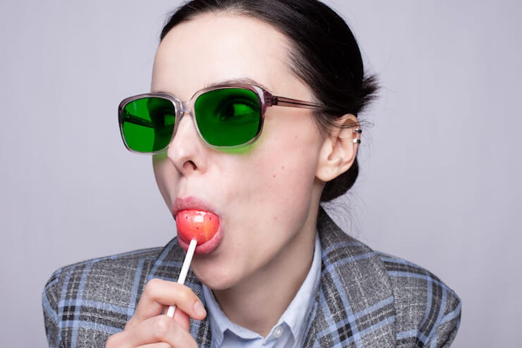 Woman in funny glasses sucking on a lollipop