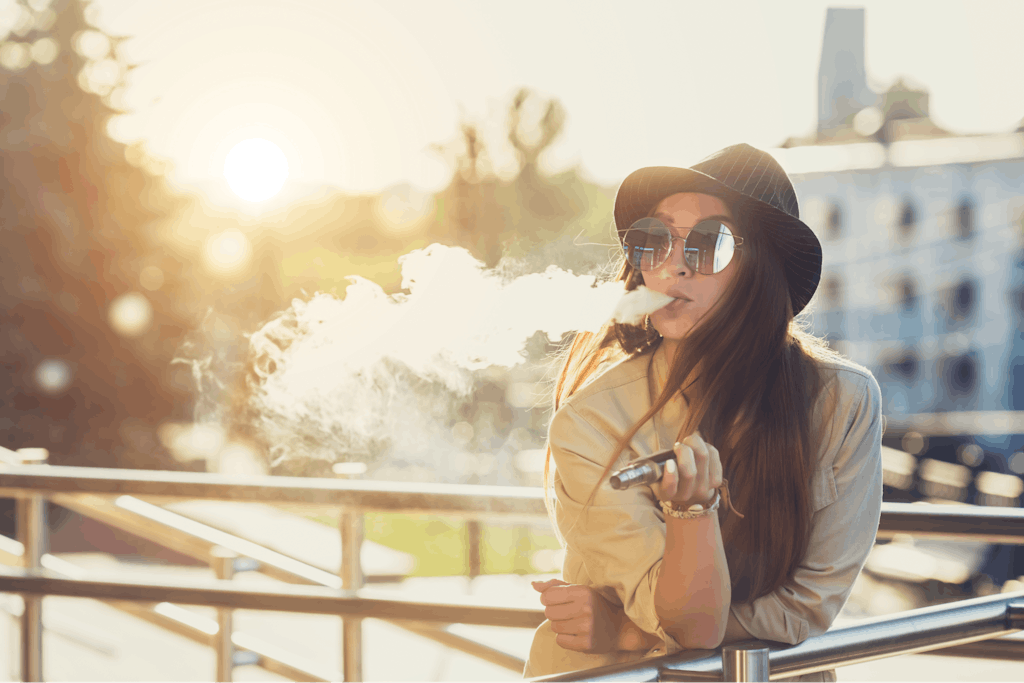 A young woman using a vaping device outdoors