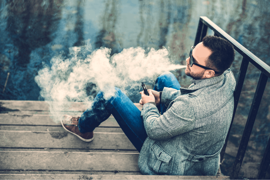 Man with beard smoking with a vape outdoors