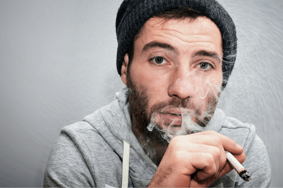 A man smoking a joint blowing smoke