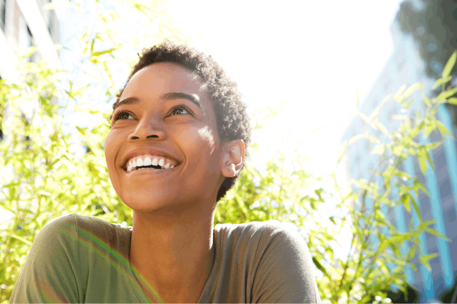 A young black woman smiling outdoors