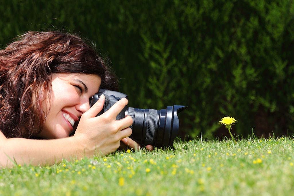 A woman takes a macro hotograph of a flower in the park 