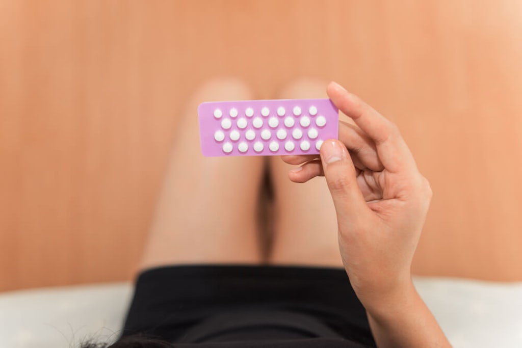 A woman looks at her birth control pills