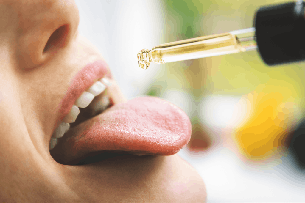 Woman taking cbd hemp oil drops in mouth from dropper