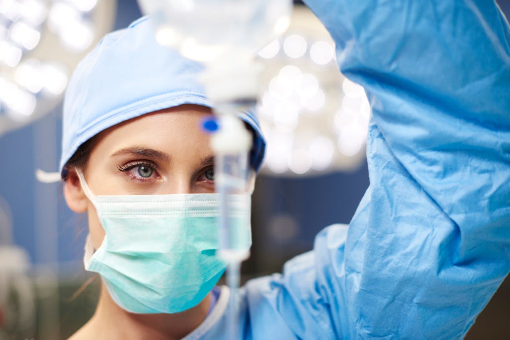 An anesthesiologist examines an IV during surgery