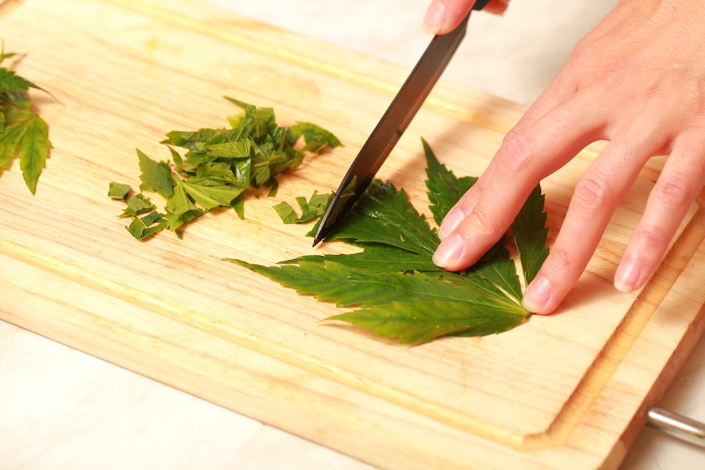 Cutting cannabis leaves on a cutting board