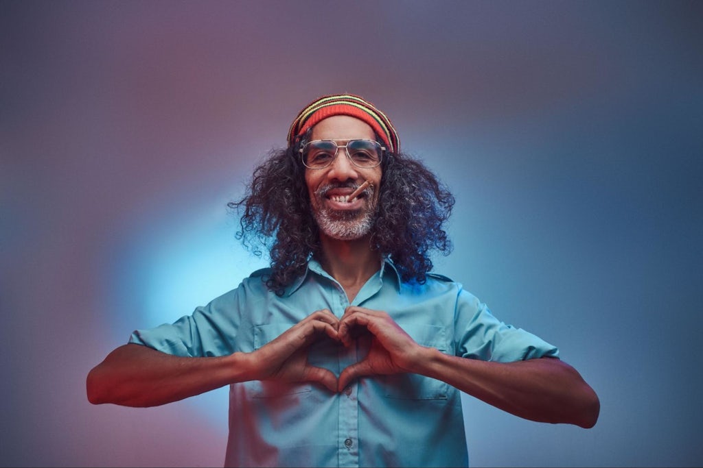 African Rastafarian smokes weed and showing heart symbol and shape with hands