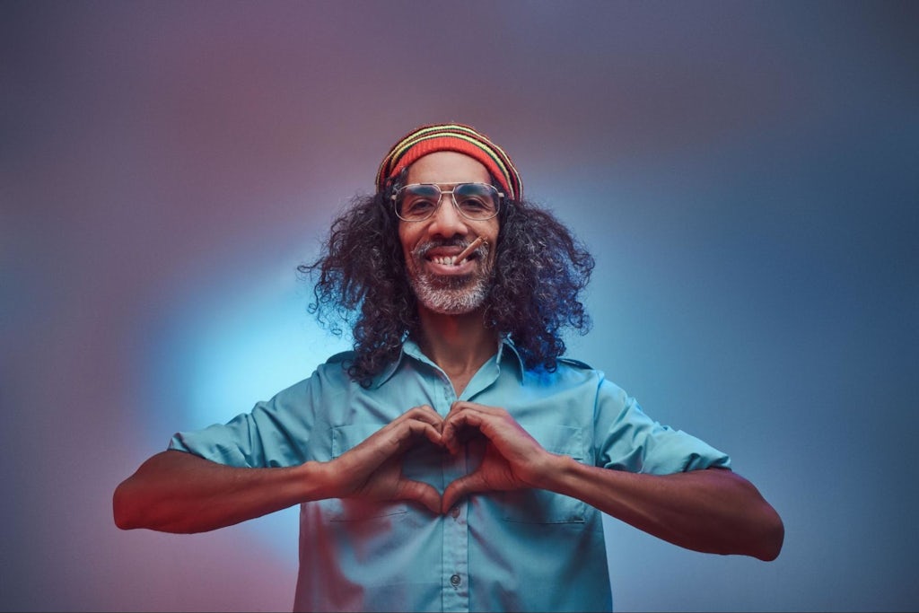 African Rastafarian smokes weed and showing heart symbol and shape with hands