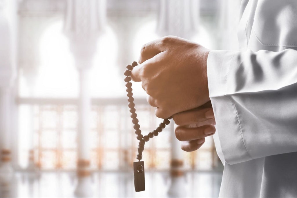 Religious muslim man praying with rosary beads